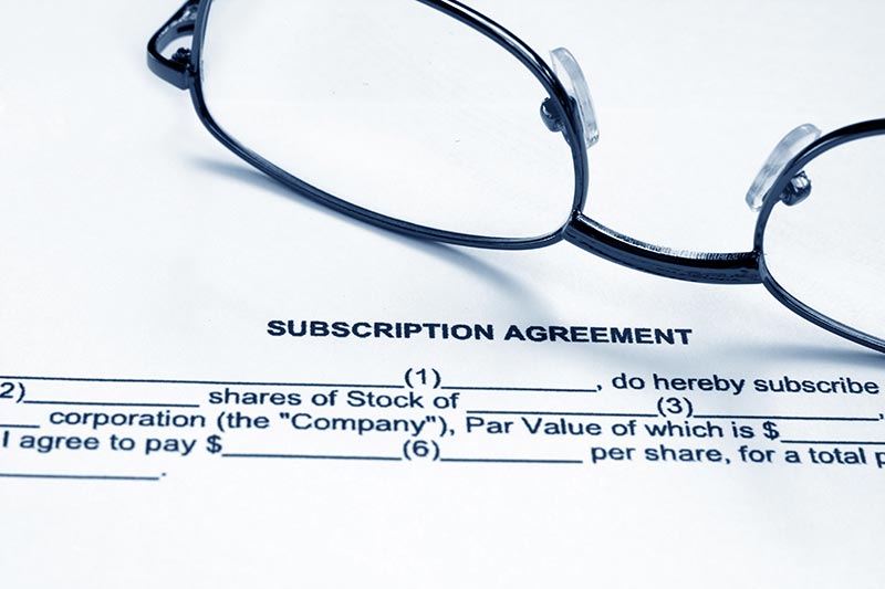 Subscription agreement text written on paper and glasses 