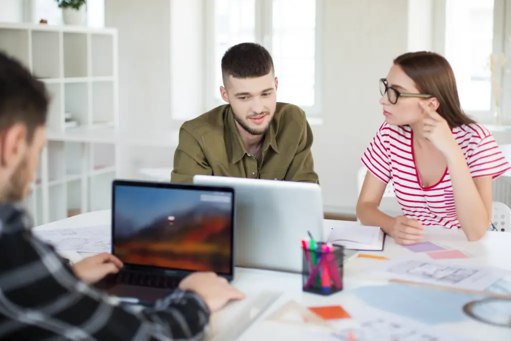 young-man-shirt-woman-striped-tshirt-eyeglasses-working-together-with-laptop-group-cool-guys-spending-time-modern-office