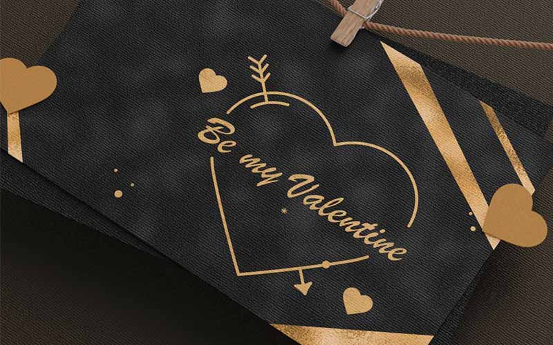 a valentines day card made using a black background with diagonal golden strips in the corners