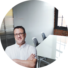 A man standing in a room with table and chairs in the background