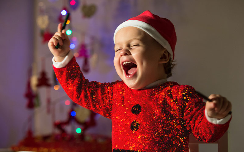 A joyous toddler wearing glittery red dress and a red Santa cap