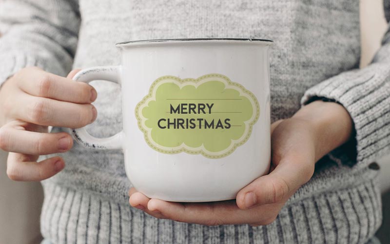 A person holding a mug with "Merry Christmas" printed on it using Christmas Vector Frame