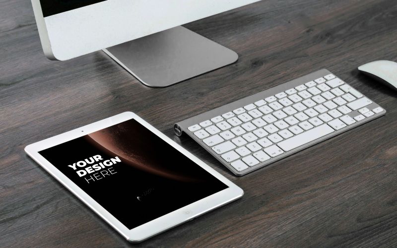 A mockup of an iPad laying on a table with a desktop and a keyboard in The Ultimate Branding Mockups Bundle