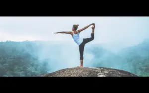 A woman doing yoga against a scenic background in this photo background changer