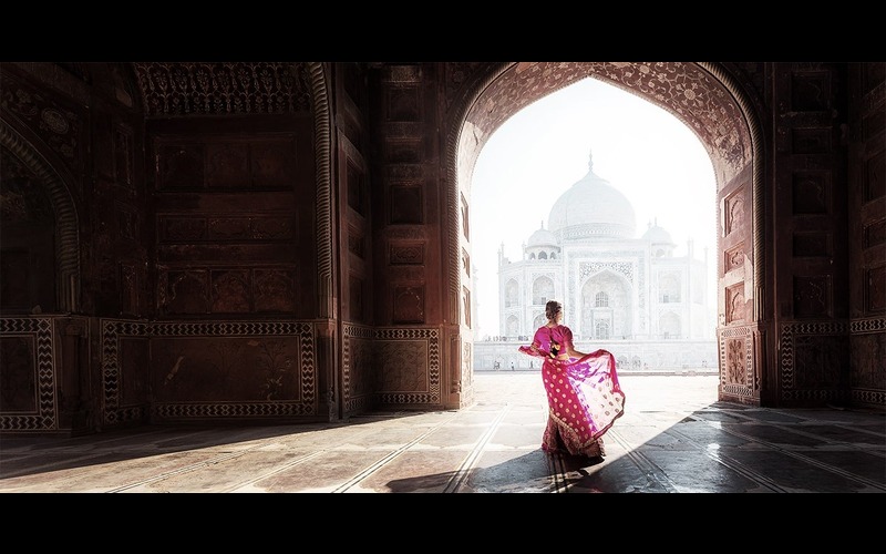 A woman in pink standing against Taj Mahal