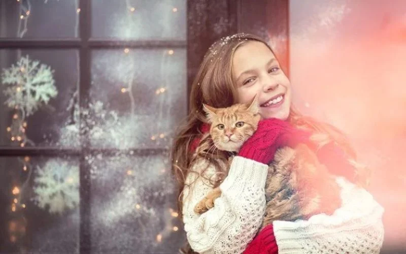 A girl in white sweater holding a ginger cat in feature image in holiday freebies blog
