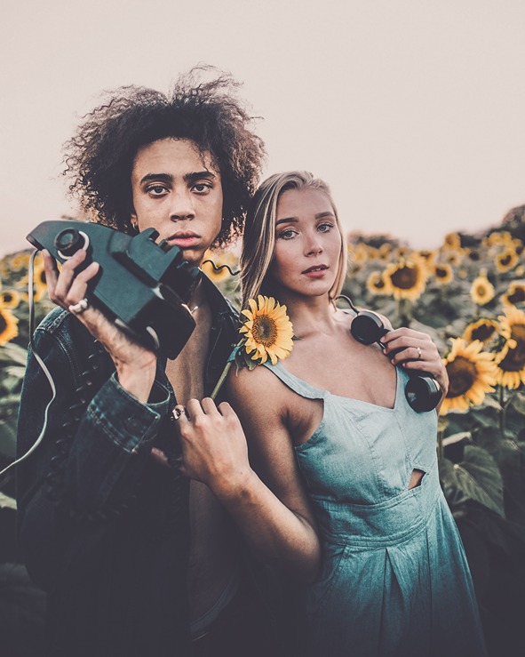 A picture of a couple in a sunflower field holding a camera