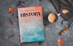 Flat lay of a "HISTORY" book with a sparkling orange-and-blue cover next to autumn decorations.