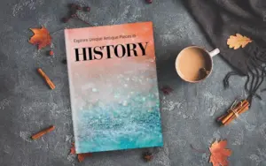Flat lay of a "HISTORY" book with a sparkling orange-and-blue cover next to autumn decorations.