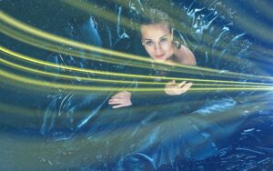 : Overhead view of a woman surrounded by dark metallic blue fabric and bright yellow light streaks.