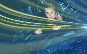 : Overhead view of a woman surrounded by dark metallic blue fabric and bright yellow light streaks.