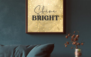 Framed vertical canvas with reddish-brown and gold abstract glitter art on a dark wall.