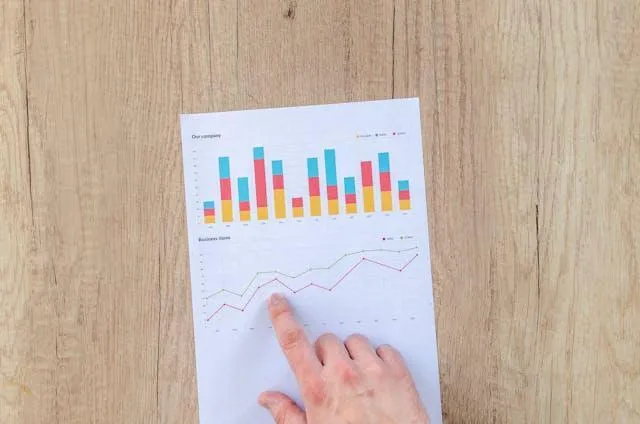 A hand pointing to a chart on a piece of paper.