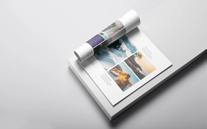 A rolled-up portfolio page resting on top of a flat, open page, showing multiple nature and travel-themed images with text boxes.