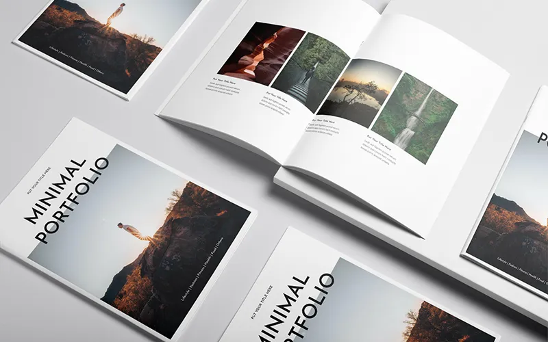A wide shot of several portfolio covers and a couple of open pages scattered on a light-colored surface, highlighting the consistent, minimal design of the templates.