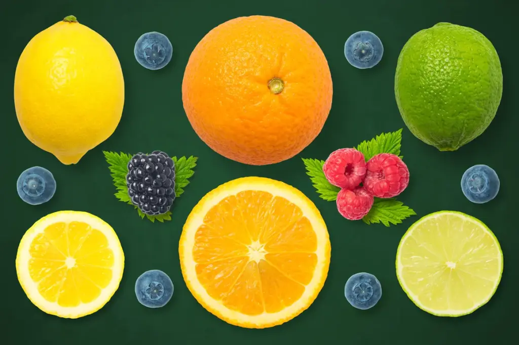 Whole and sliced lemon, lime, and orange surrounded by blueberries, raspberries, blackberry, and green leaves on a dark green background