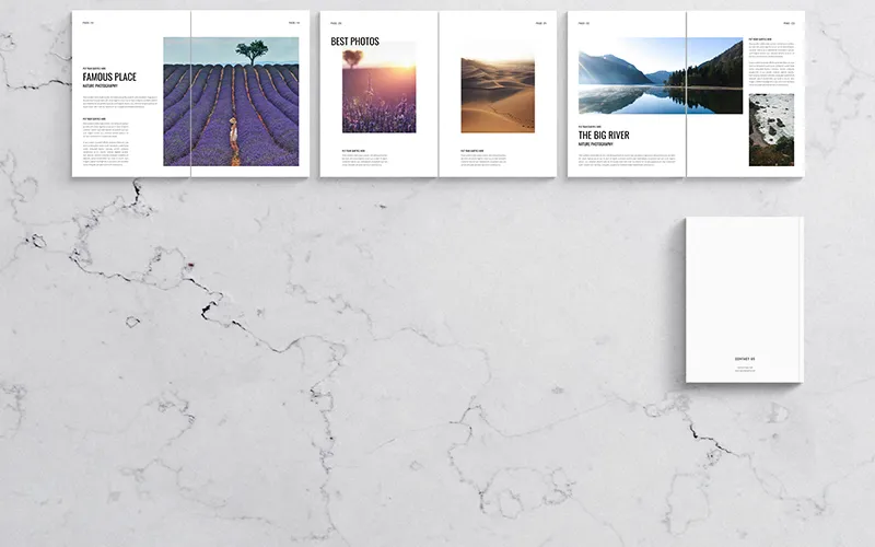 Several open white photography portfolio books displaying images of landscapes, mountains, and seascapes.