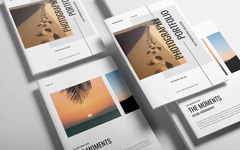 Several photography portfolio covers and open pages featuring desert footprints and sunset images, arranged on a light surface.