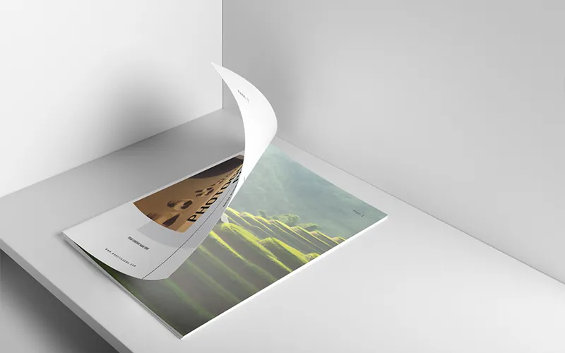 Close-up of multiple white portfolio covers and open pages, featuring desert and terraced field photography layouts.