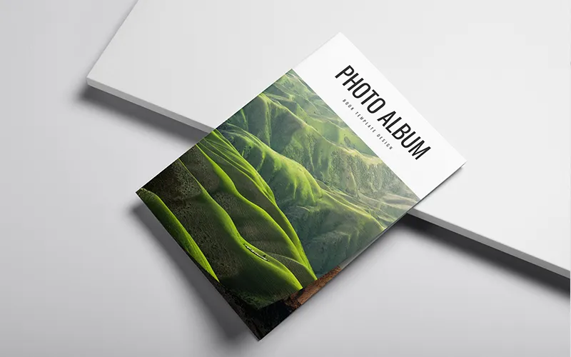 Photo album with green hills cover on white surface