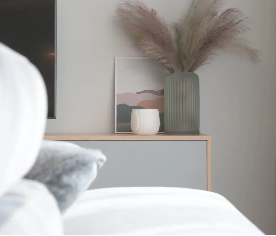 Home decor featuring pampas grass in a fluted vase next to a framed artwork.