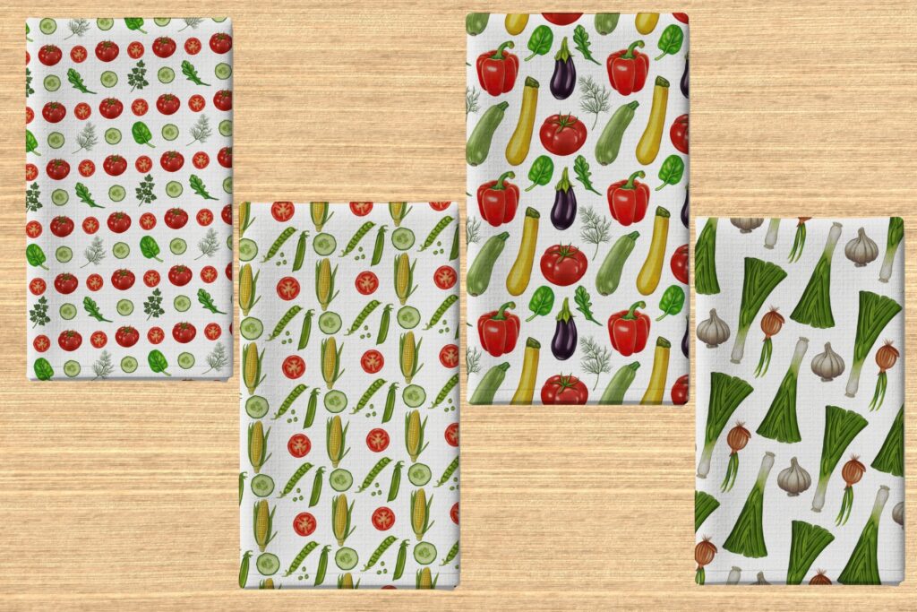 Four kitchen towels with vibrant vegetable patterns like corn, eggplant, and leeks